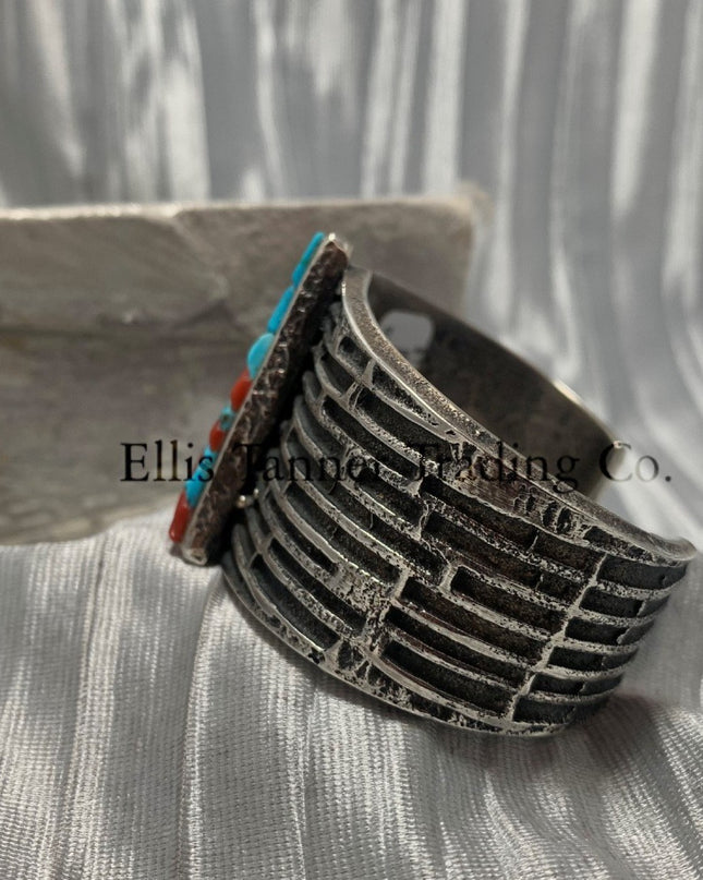 Displayed is the side of a silver tufa cobbletone bracelet, on a silver shiny sheet,
