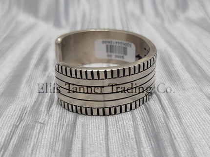 Side View of a heavy silver stamped bracelet, placed on a silver cloth 
