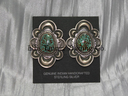 Silver stamped clip on earrings, with a center #8 Turquoise surrounded by a silver rope. displayed on a black card on top of a silver sheet 