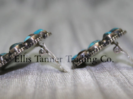 Cluster-style sterling silver clip-on earrings side view, displayed on a black card against a silver satin background.