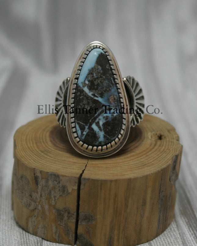 Tommy Jackson Black Diamond Turquoise Teardrop Stone silver overlay sides on top of a wooden display Front View 