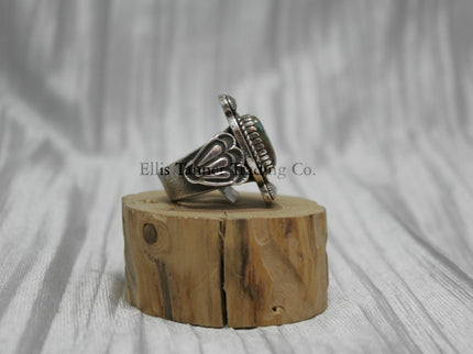 Tommy Jackson Square Royston Turquoise, silver band with silver stamped overlay, on top of a wooden display, side view 