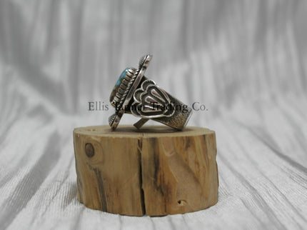 Tommy Jackson Square Royston Turquoise, silver band with silver stamped overlay, on top of a wooden display, side view 