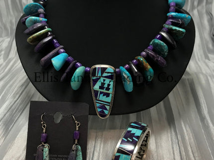 A Southwest-style jewelry set featuring a vibrant beaded necklace, earrings, and cuff bracelet. The necklace has Sleeping Beauty turquoise, purple sugilite stones, with a central pendant showcasing intricate geometric inlay work. The matching drop earrings feature Sleeping Beauty turquoise and purple Sugilite beads. The cuff bracelet highlights bold geometric patterns set in sterling silver.